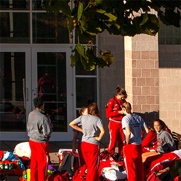 Student athletes wait outside Bartels Hall with their gear